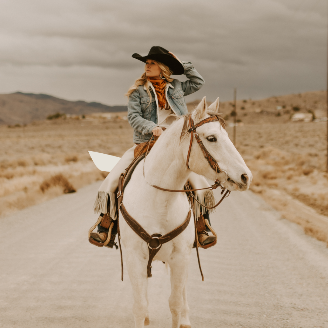 cowgirl on horse in denim jacket and black cowboy hat