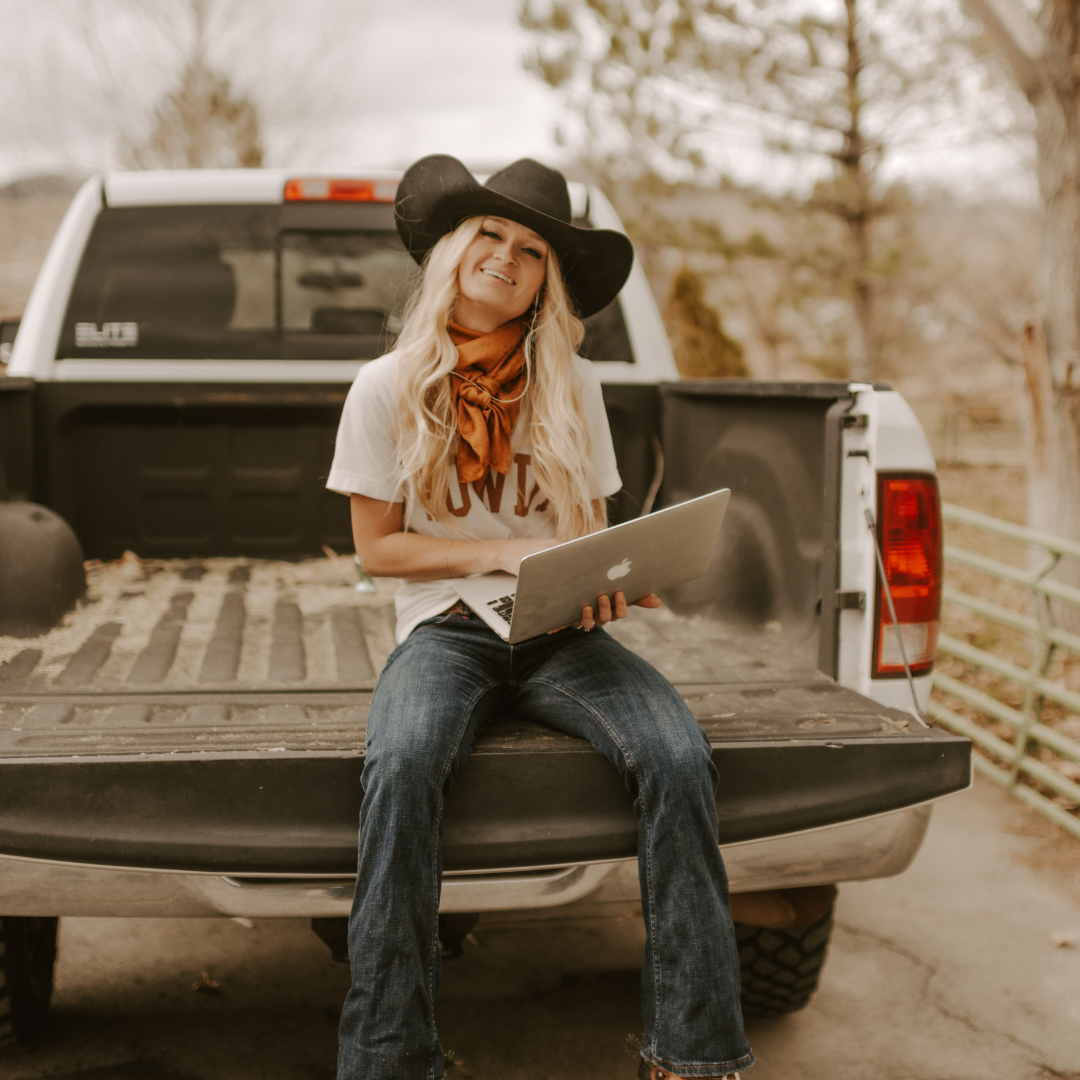 cowgirl with laptop sitting on a tailgate